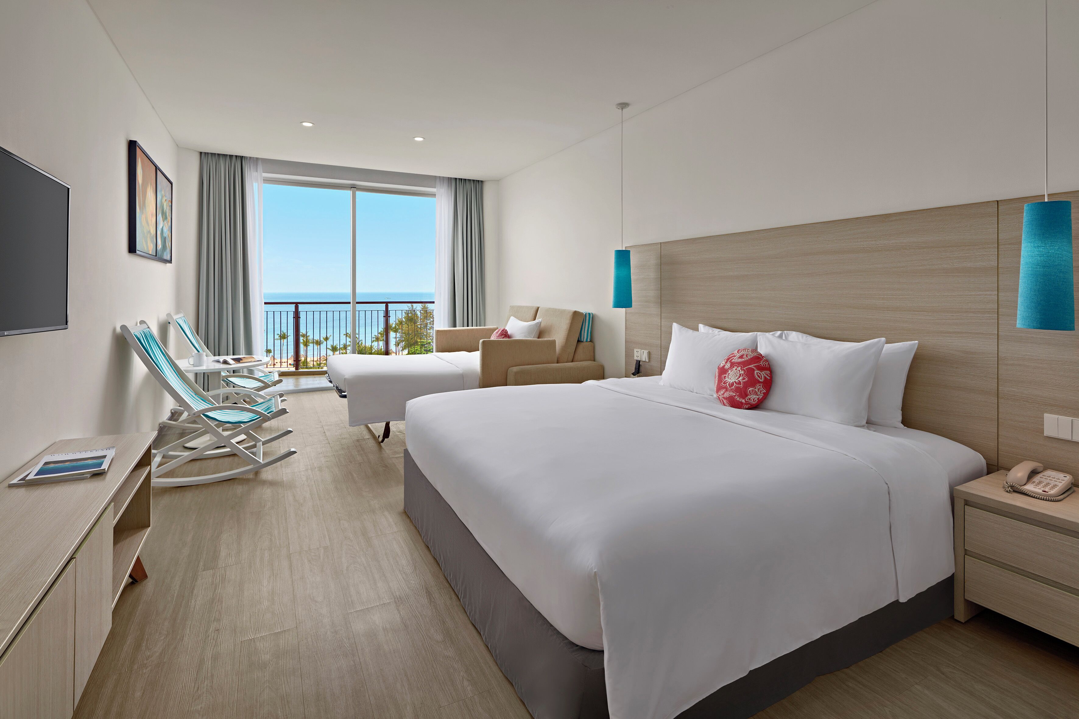 Een moderne hotelkamer met een groot bed, een bureau, een stoel en een balkon met uitzicht op zee.