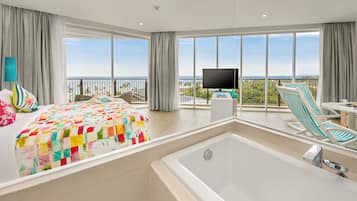Une chambre d’hôtel moderne dotée d’un grand lit, d’une baignoire, d’une télévision et d’un balcon offrant une vue sur l’océan.