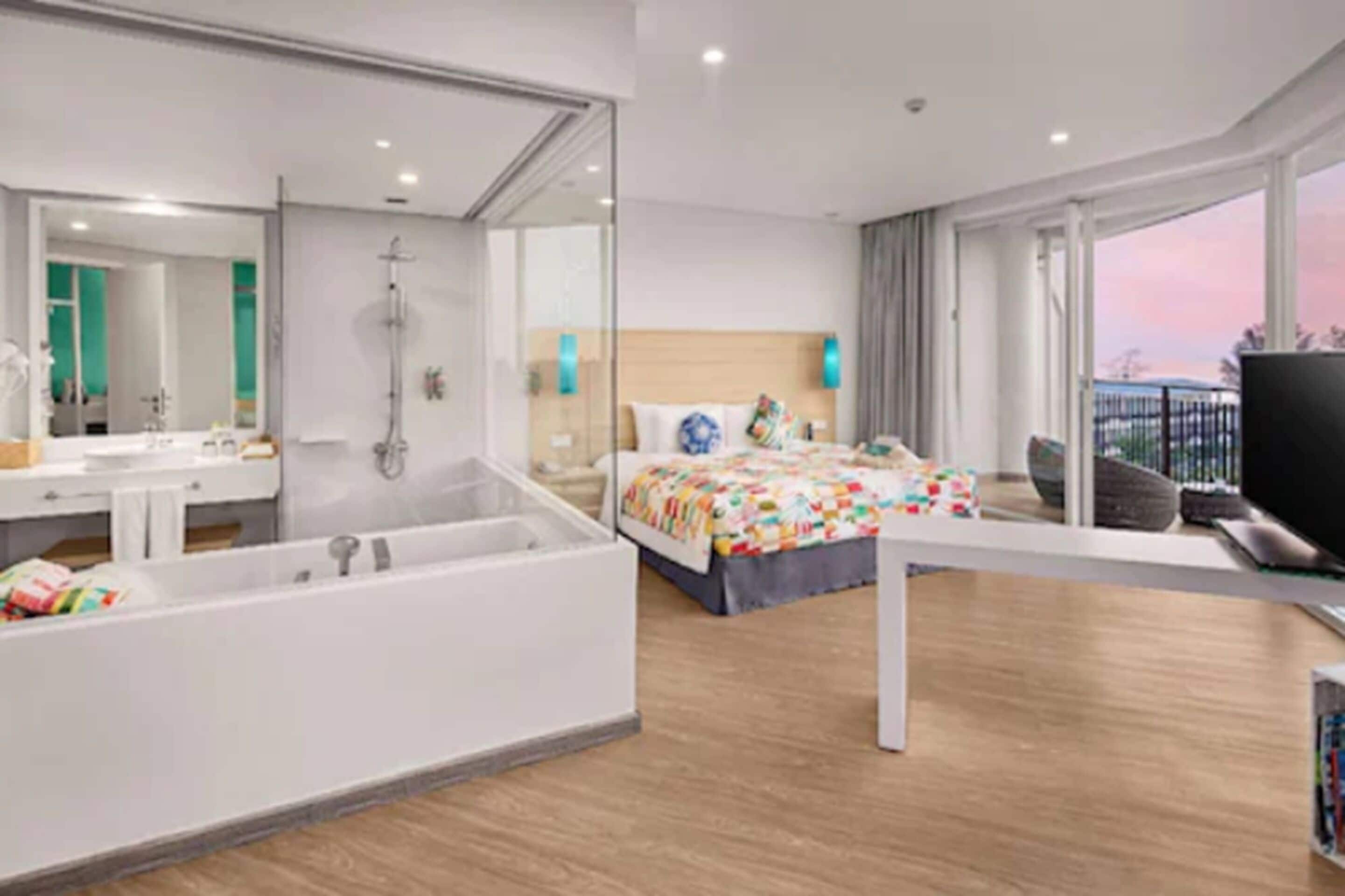 Una habitación de hotel moderna con una cama grande, una bañera, un escritorio y un televisor.