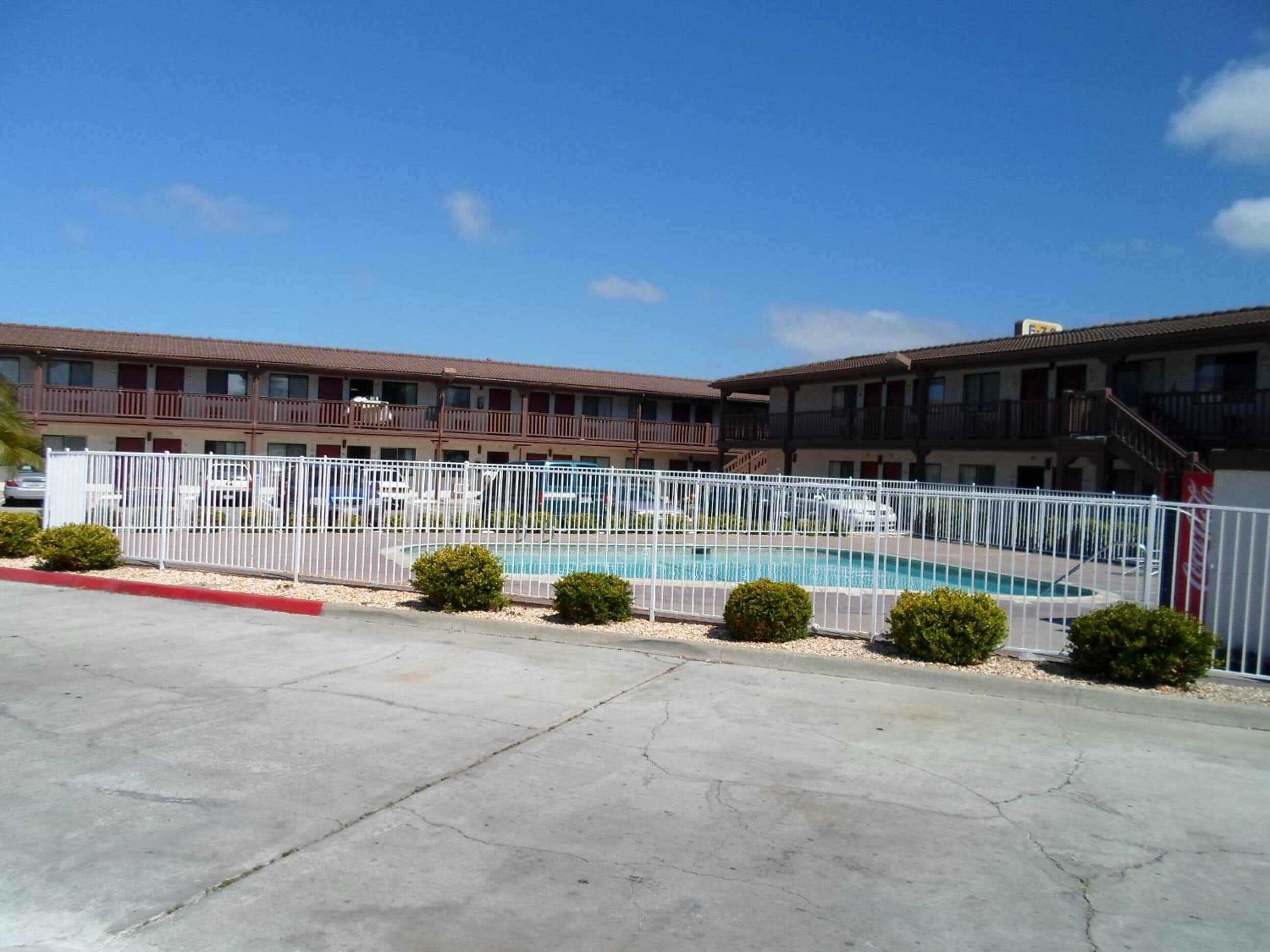 Un motel con piscina, parcheggio recintato e cordolo rosso.