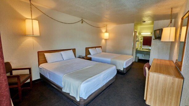 A hotel room with two beds, a desk, and a mirror.