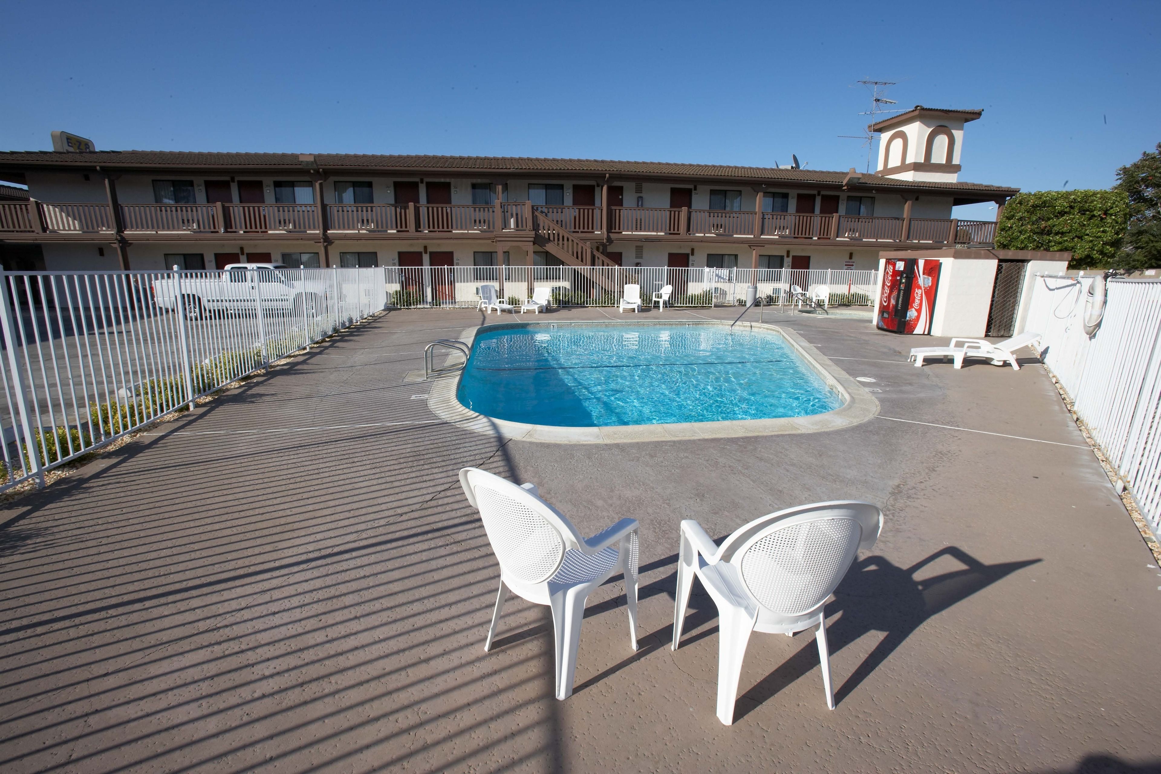 Area piscina con lettini e un edificio sullo sfondo.