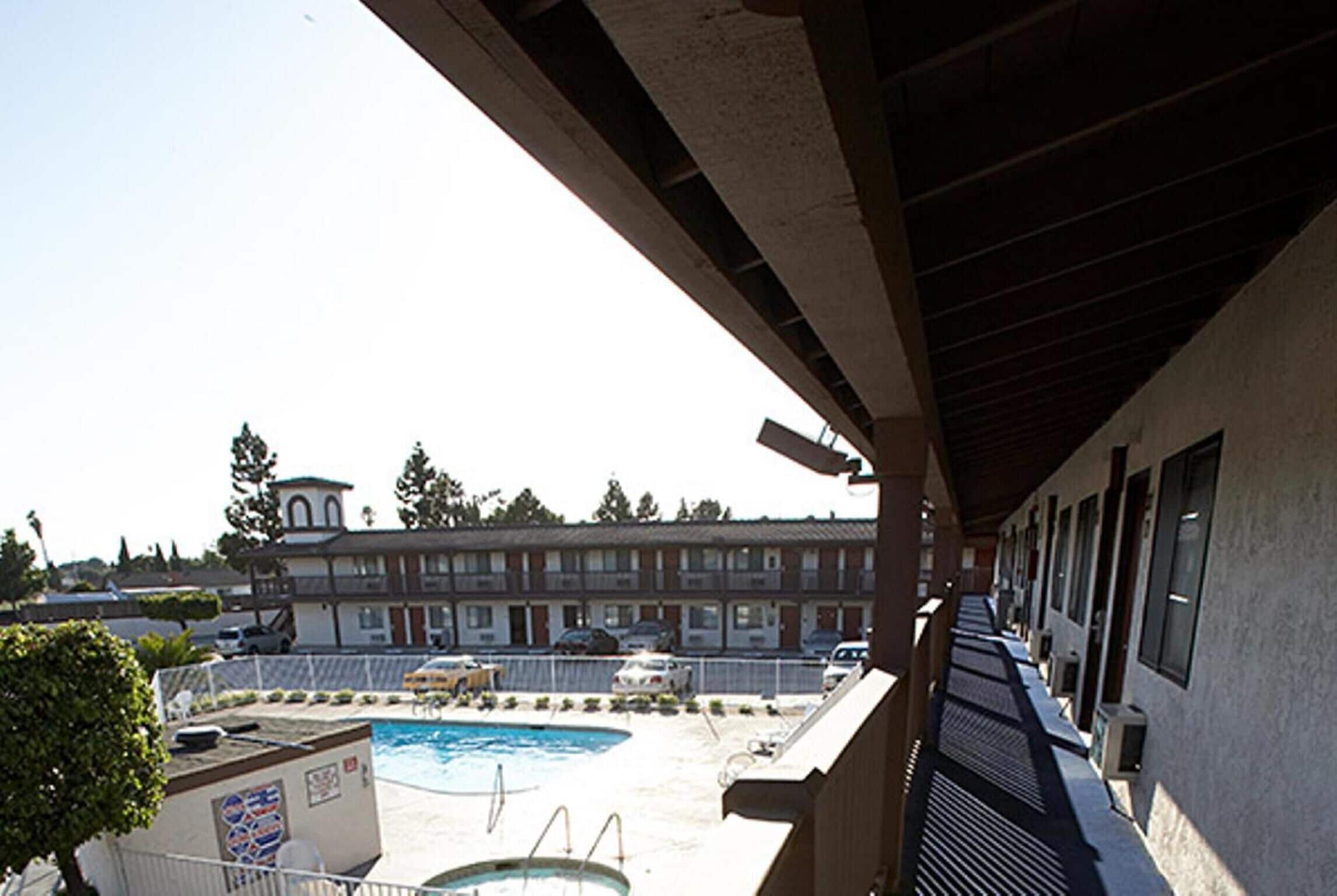 A hotel with a pool area, a covered walkway, and a building with multiple windows and balconies.