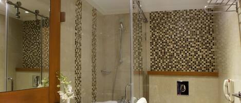 A modern bathroom with a marble sink, a glass shower enclosure, and a toilet.