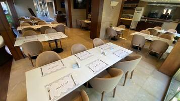 A restaurant with multiple tables set for dining, featuring a modern interior with a mix of natural and artificial lighting.