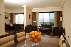 Enjoy ocean views from the large window, relax in the seating area with sofas and coffee table, and unwind with a refreshing drink.