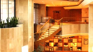 A multi-level interior with a staircase, seating areas, and a reception desk.