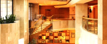 A multi-level interior with a staircase, seating areas, and a reception desk.