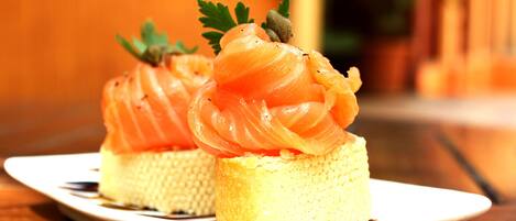 Two small cakes with salmon on top, garnished with parsley, on a white plate.