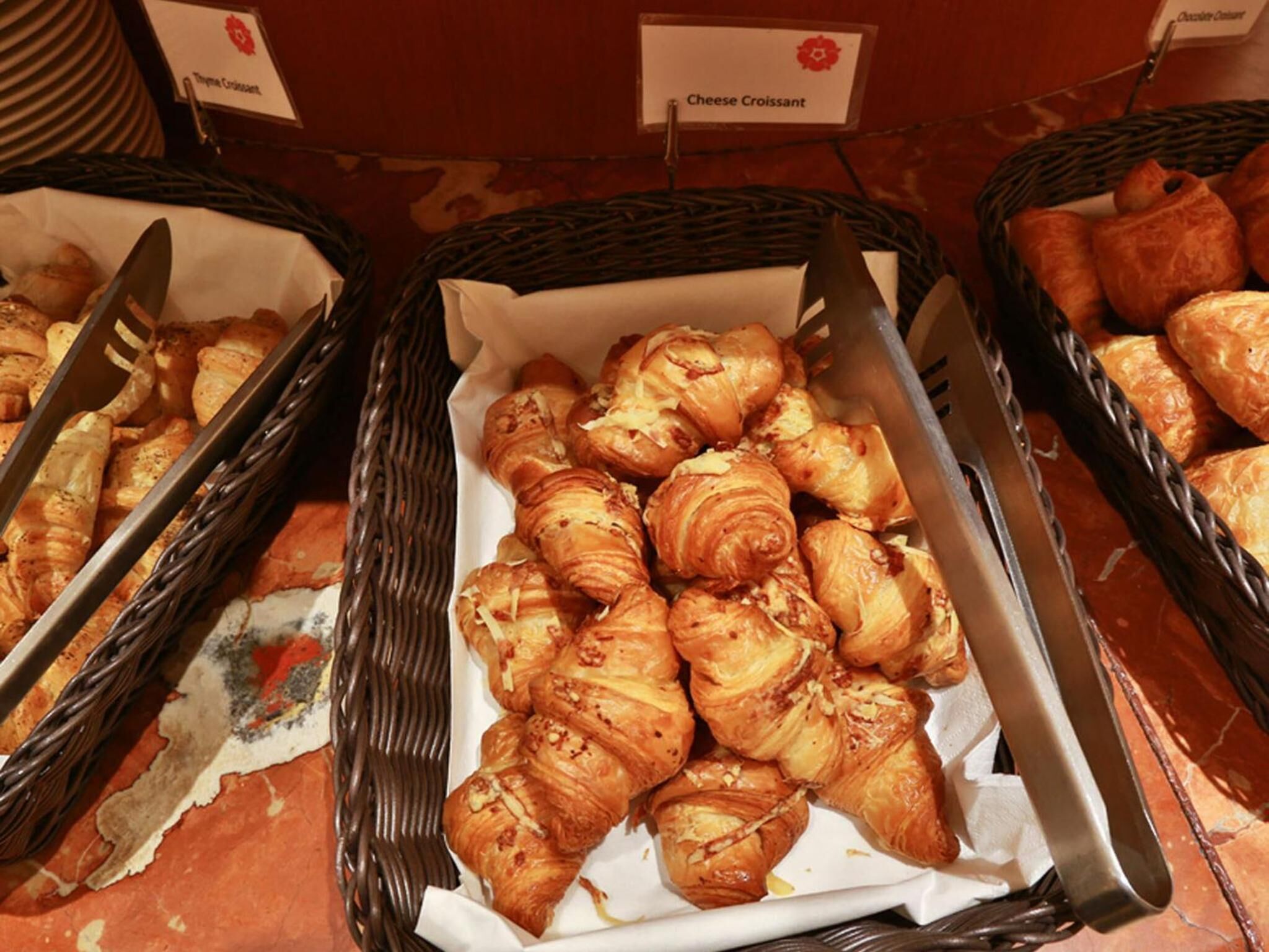 A buffet with baskets of croissants and cheese croissants.
