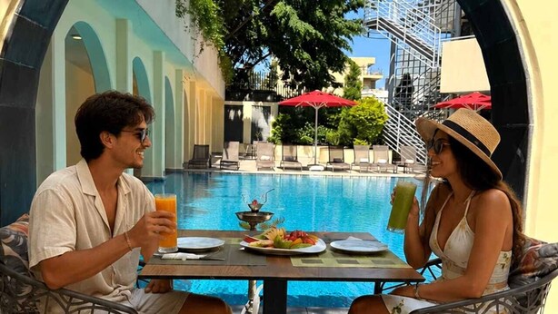 A poolside dining area with a table, chairs, and a view of the pool.