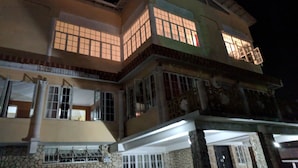 Un edificio de varios pisos con amplias ventanas y balcones, que presenta una fachada de piedra y un techo plano.
