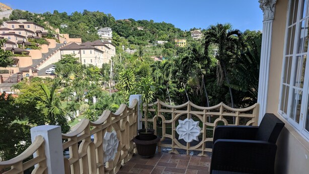 Un balcón con vistas a una colina con casas, una valla de madera y una planta en maceta.