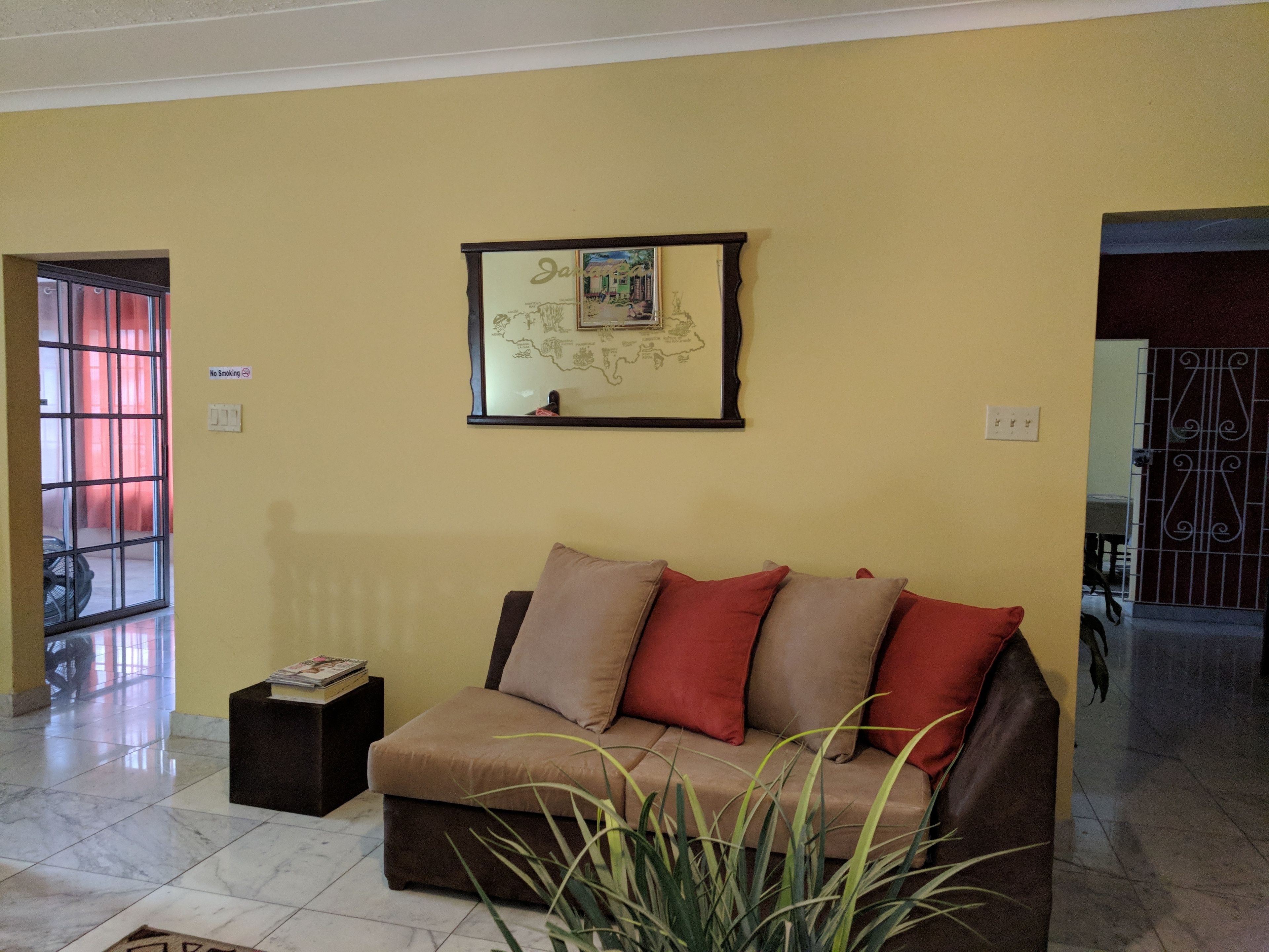 A living room with a sofa, a framed map on the wall, and a 'No Smoking' sign.