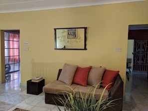 A living room with a sofa, a framed map on the wall, and a 'No Smoking' sign.