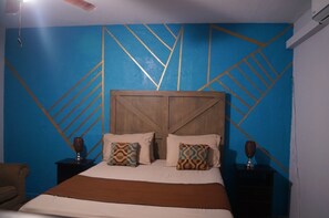 A bed with a wooden headboard, two nightstands with decorative items, and a blue wall with geometric patterns. - Rockhampton Retreat Guest House (Kingston)