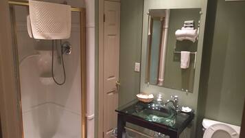 A bathroom with a glass sink, a toilet, and a walk-in shower.