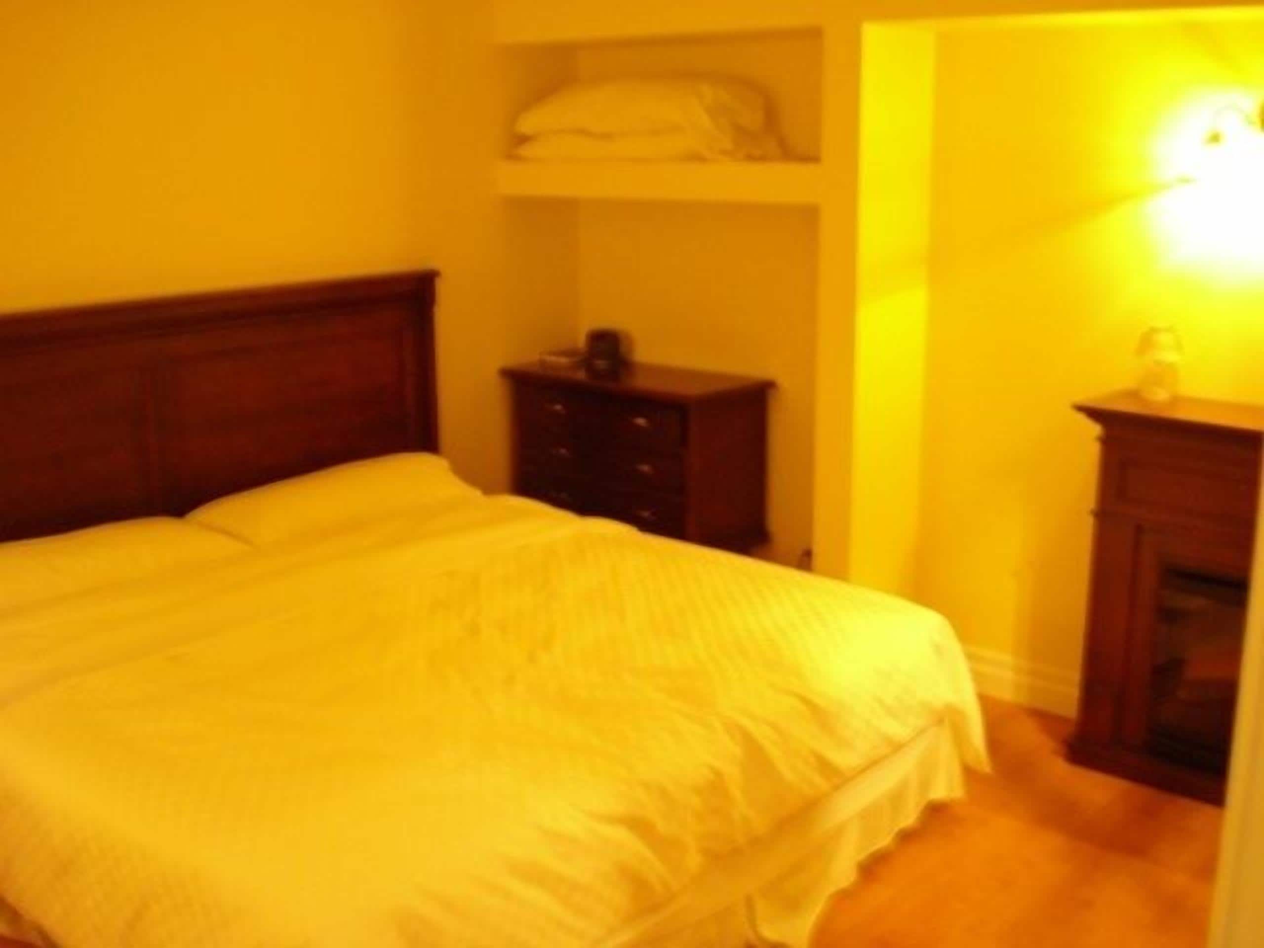 A bedroom with a large bed, a dresser, and a nightstand.