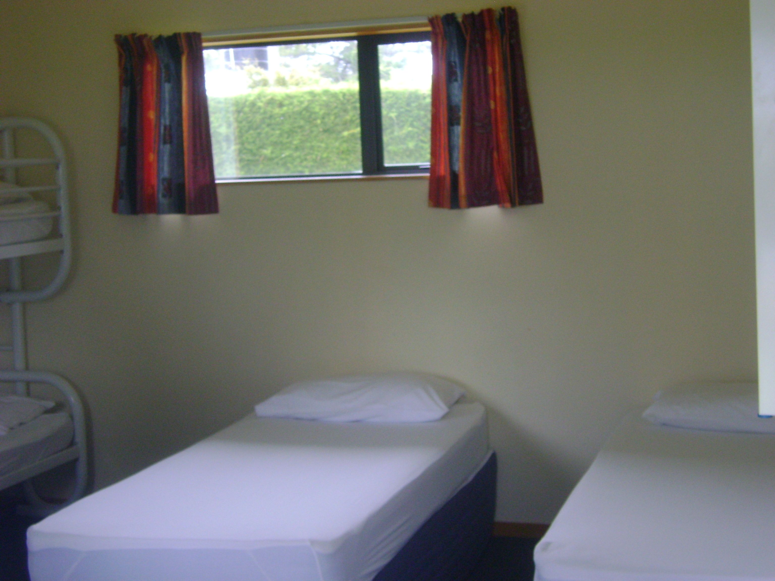 A room with two single beds, a window with curtains, and a white radiator.