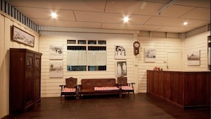 A room with a wooden bench, a wooden cabinet, and a clock on the wall. - Baan Chang Ton (Surin)