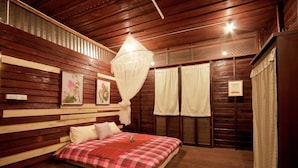 A wooden room with a bed, a hanging light fixture, and framed pictures on the wall. - Baan Chang Ton (Surin)