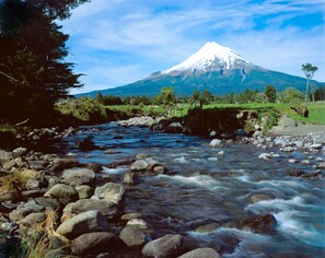 Un río que serpentea a través de un paisaje rocoso, con una montaña nevada al fondo.