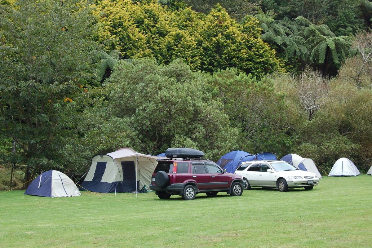 A campsite with tents and cars parked on a grassy field.