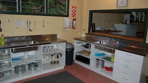 A kitchen with stainless steel countertops, white cabinets, and a large mirror. There are various kitchen utensils and appliances visible.