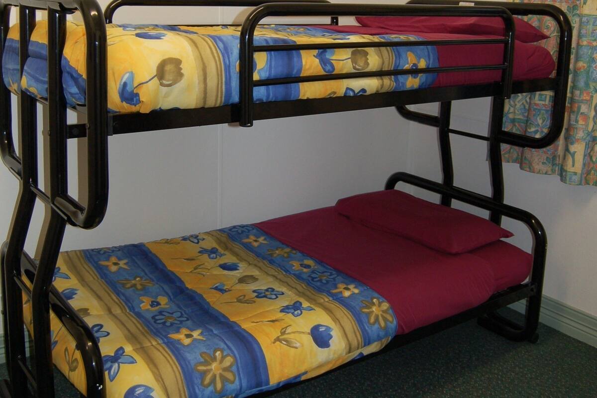 A bunk bed with floral-patterned bedding in a room with plain walls and a carpeted floor.