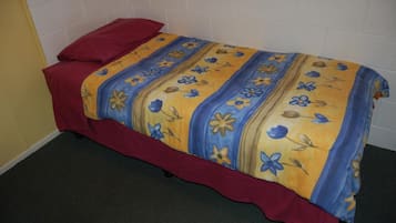 A single bed with a red headboard and a floral-patterned bedspread.