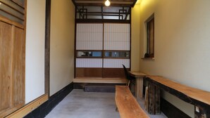 Una habitación japonesa tradicional con suelo de tatami, un banco de madera bajo y puertas correderas shoji.