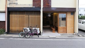 Un edificio con cerca de madera, una bicicleta y una banca afuera.