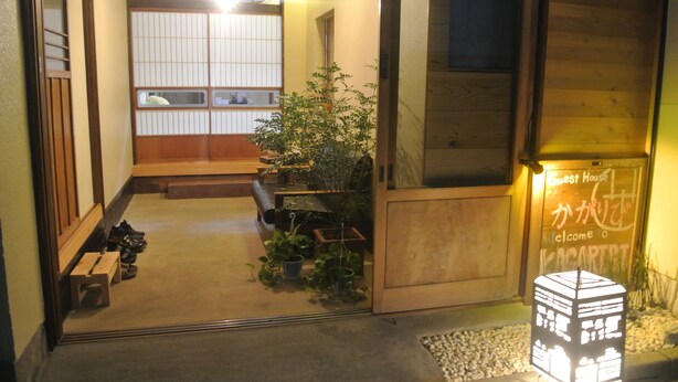 Una posada japonesa tradicional con fachada de madera, un mostrador de recepción y un cartel dando la bienvenida a los huéspedes.