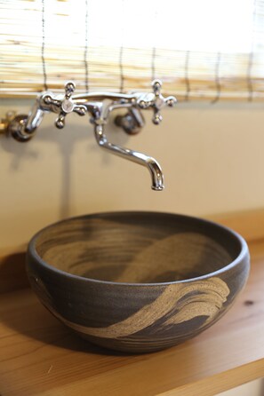 A ceramic bowl sink with a vintage faucet mounted on a wooden shelf. - Kagaribi Guesthouse - Hostel (Tokyo)
