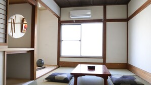 Una habitación tradicional japonesa con suelo de tatami, una mesita baja, cojines y un fusuma.