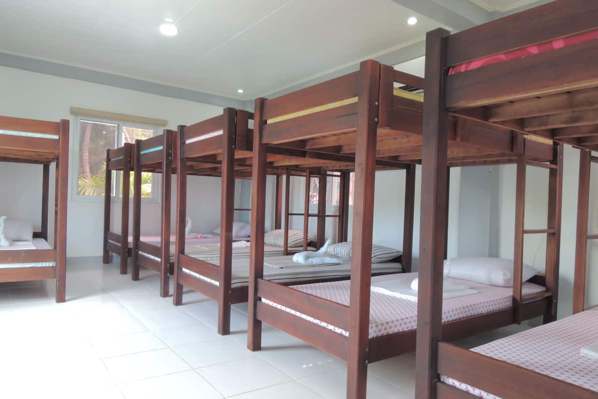 Una habitación de hotel con varias literas y un ventanal grande.