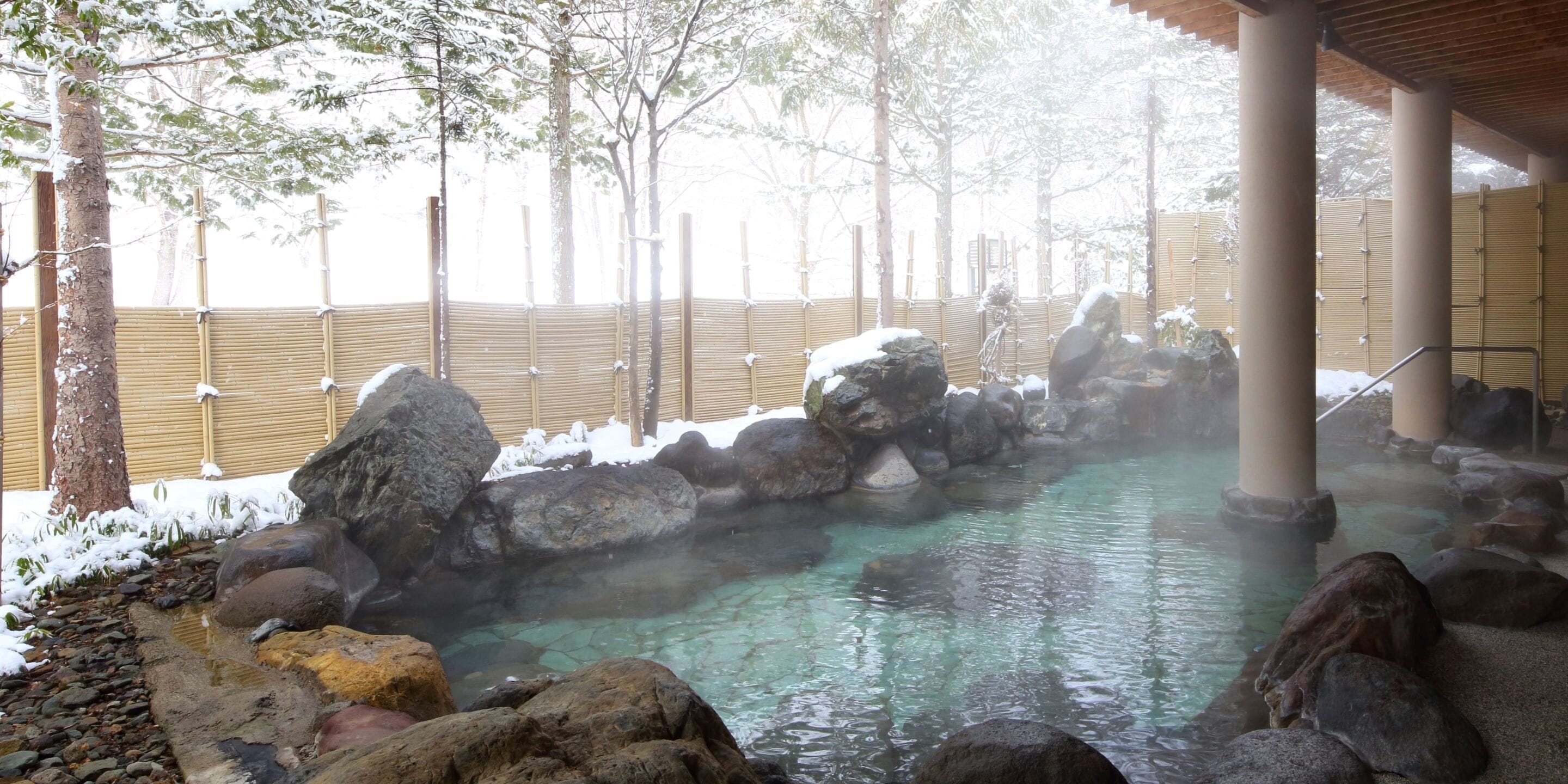 A hot spring area with large rocks and a wooden fence.