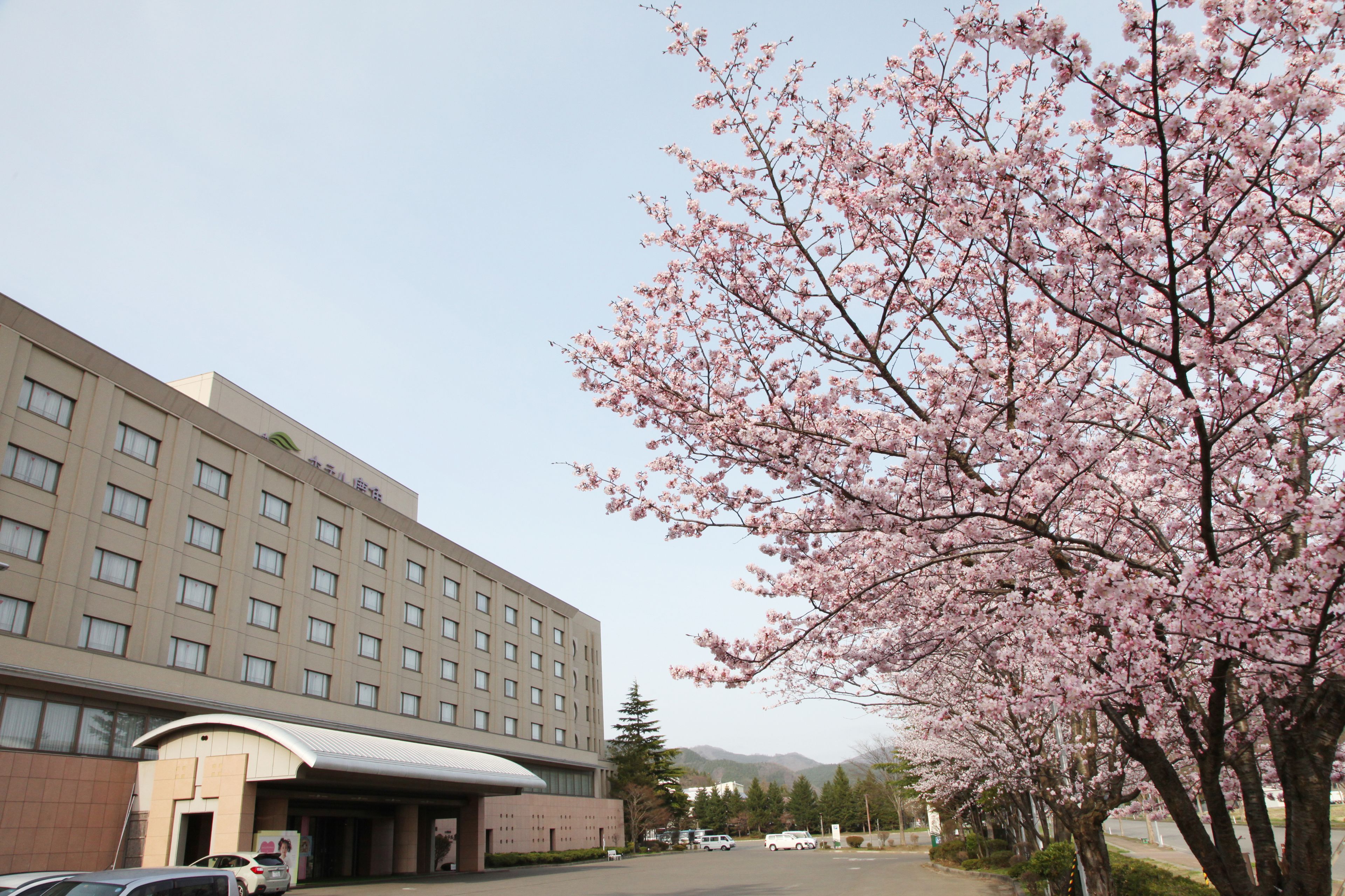 A large hotel with multiple floors and a parking lot in front.