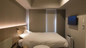 Una habitación de hotel moderna con una cama grande, una pequeña mesa redonda, un televisor montado en la pared y un calentador integrado.