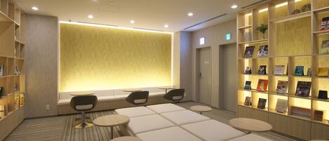 A modern lounge area with seating, bookshelves, and a large illuminated wall.