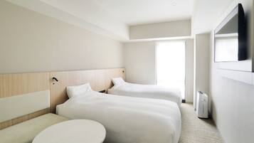 A hotel room with two beds, a round table, a flat-screen TV, and a window.