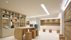 Una recepción moderna con un mostrador de madera, diversas opciones de asientos y un diseño limpio y minimalista.