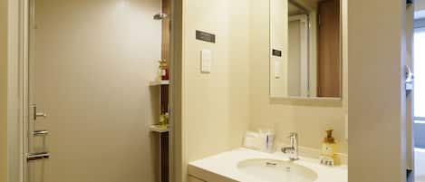 Un baño con lavamanos blanco, espejo y zona de ducha.