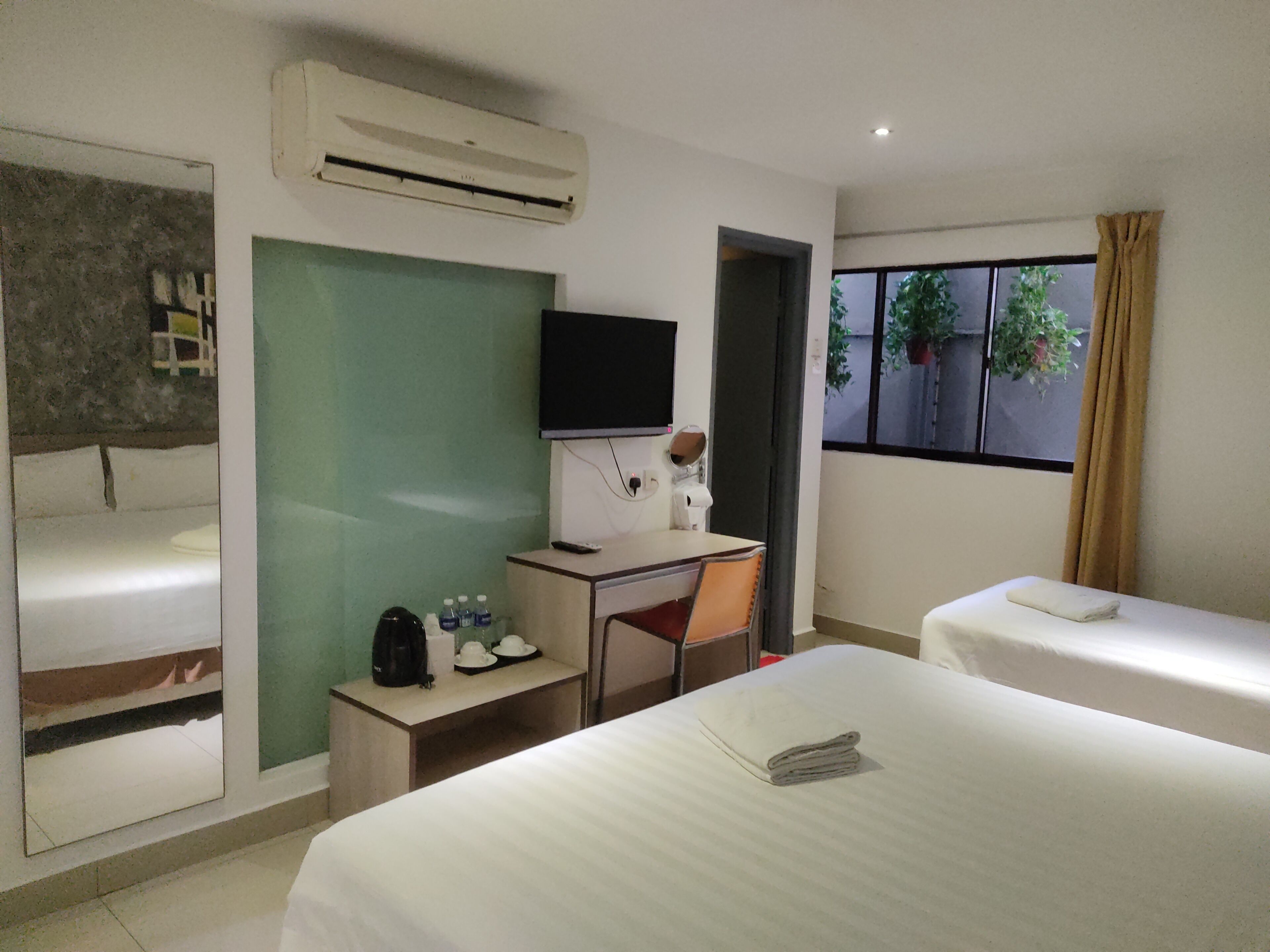 Une chambre d’hôtel avec un lit, un bureau et une chaise, une télévision et une fenêtre avec des rideaux.