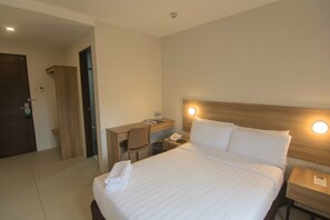 A hotel room with a bed, a desk, a chair, and a nightstand. - Mango Suites - Tuguegarao (Tuguegarao)
