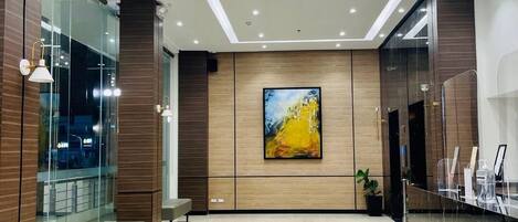 Un vestíbulo moderno con piso de mármol, un cuadro abstracto de gran tamaño y una zona de estar.
