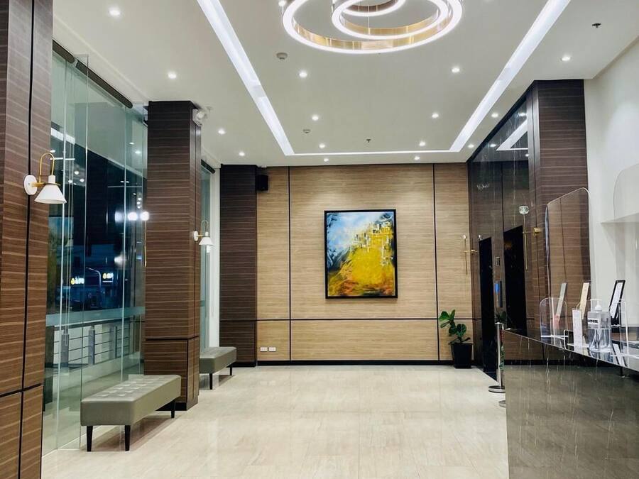 A modern lobby with a marble floor, a large abstract painting, and a seating area.