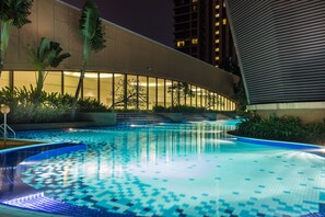 A swimming pool with a tiled pattern, surrounded by plants and a modern building with large windows. - Rainbow Suites at Times Square (Kuala Lumpur)