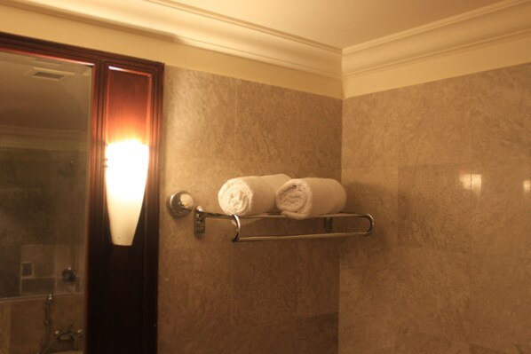 A bathroom with a towel rack holding two rolled towels, a mirror, and a light fixture above the mirror. - Rainbow Suites at Times Square (Kuala Lumpur)