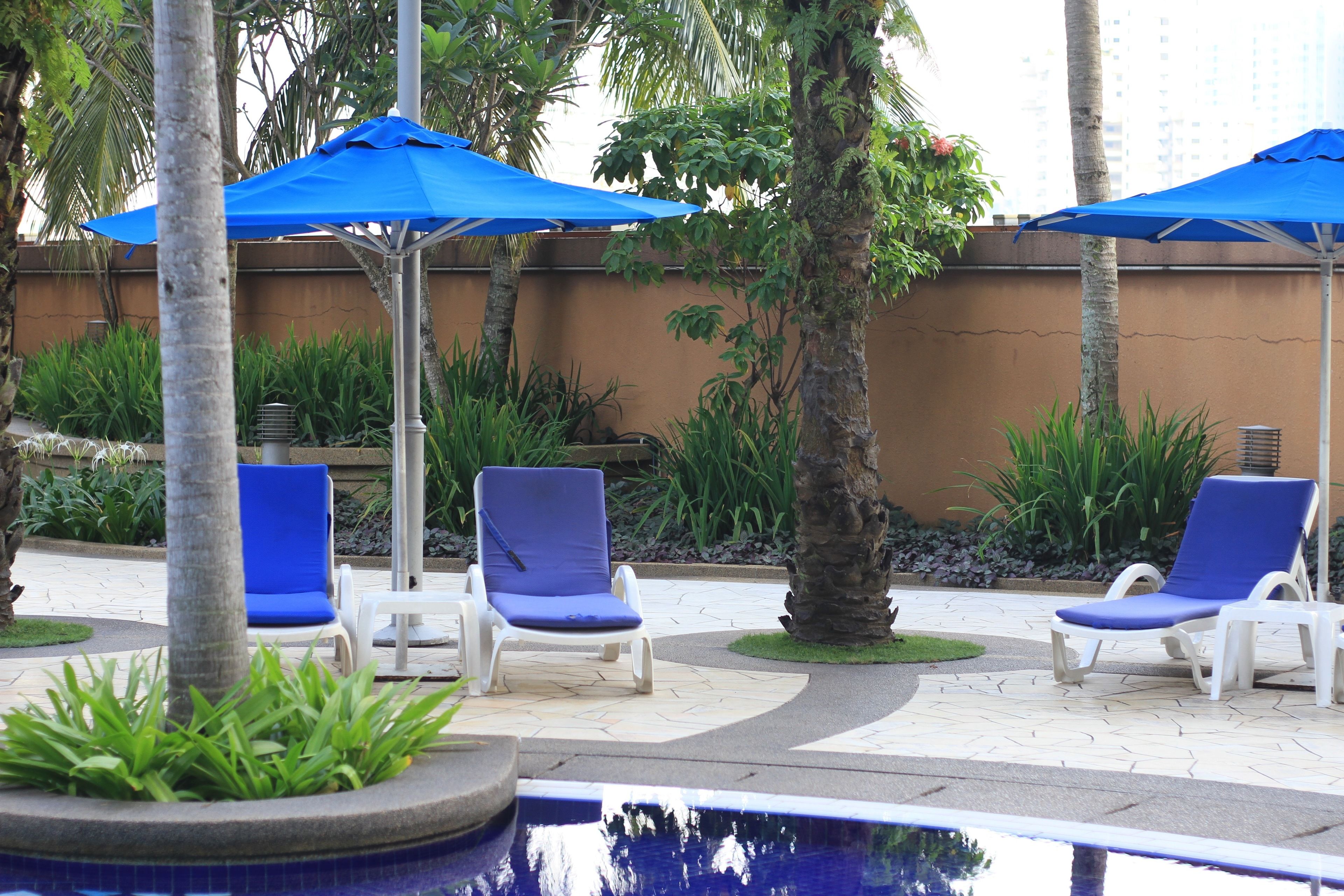 A poolside area with lounge chairs and blue umbrellas.